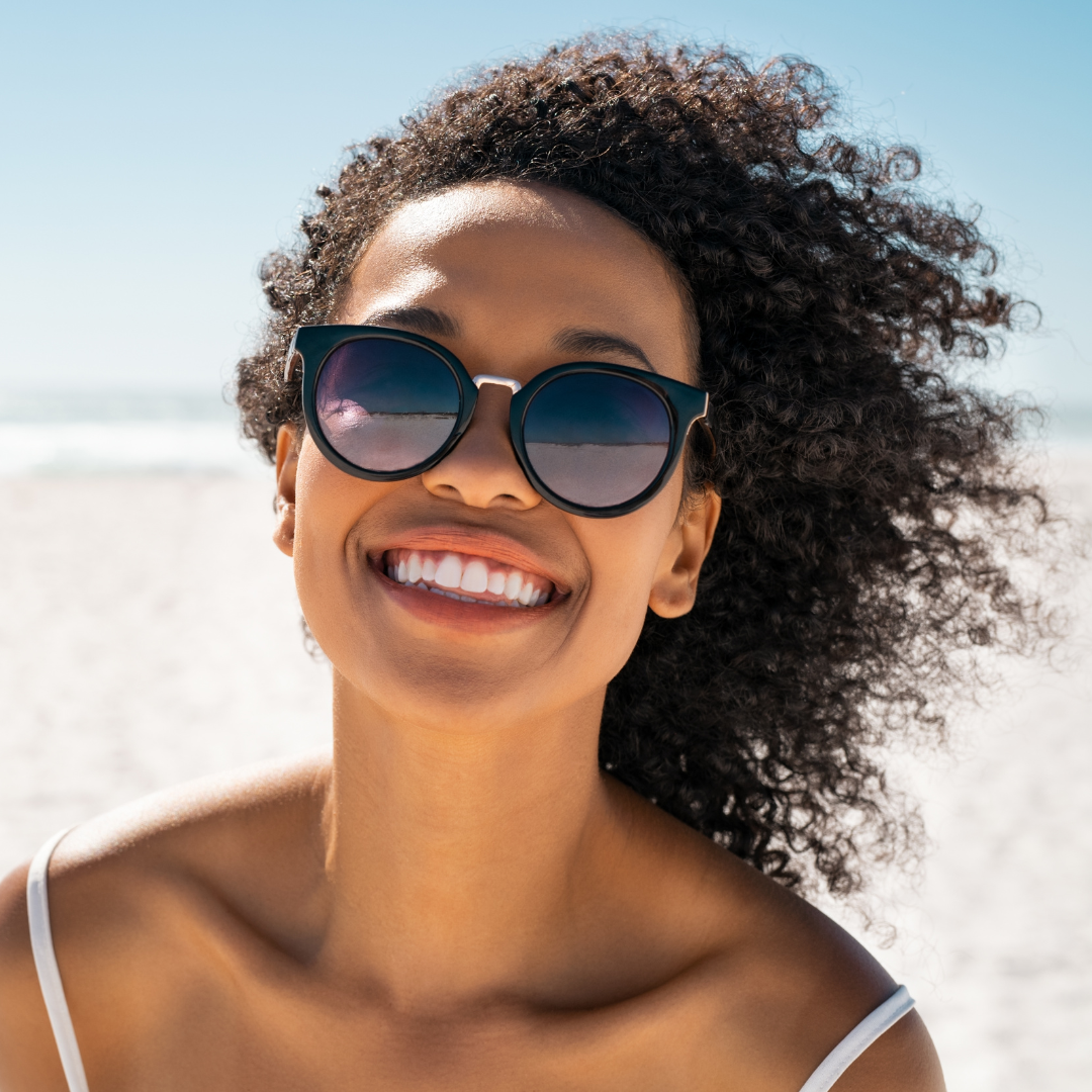 A smiling woman on the beach in sunglasses