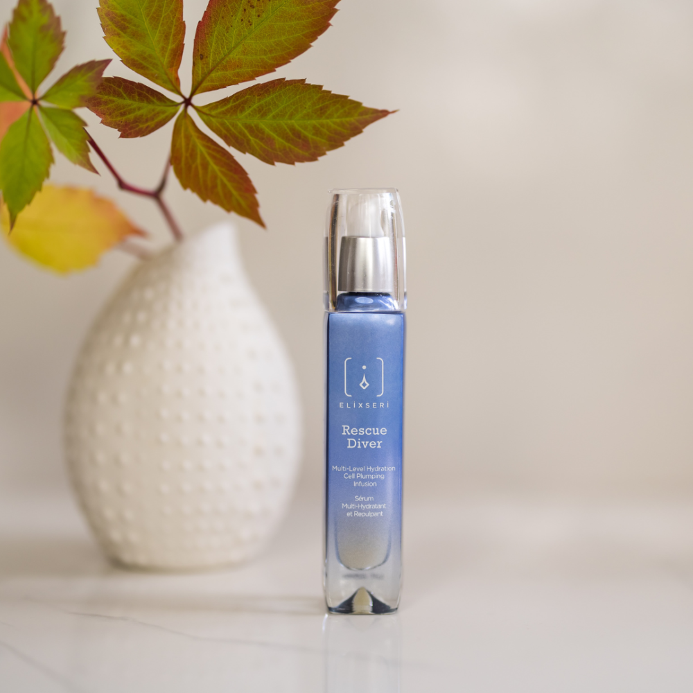Elixseri Rescue Diver hydrating and cell plumping serum on a white background in front of a white vase with Autumn leaves