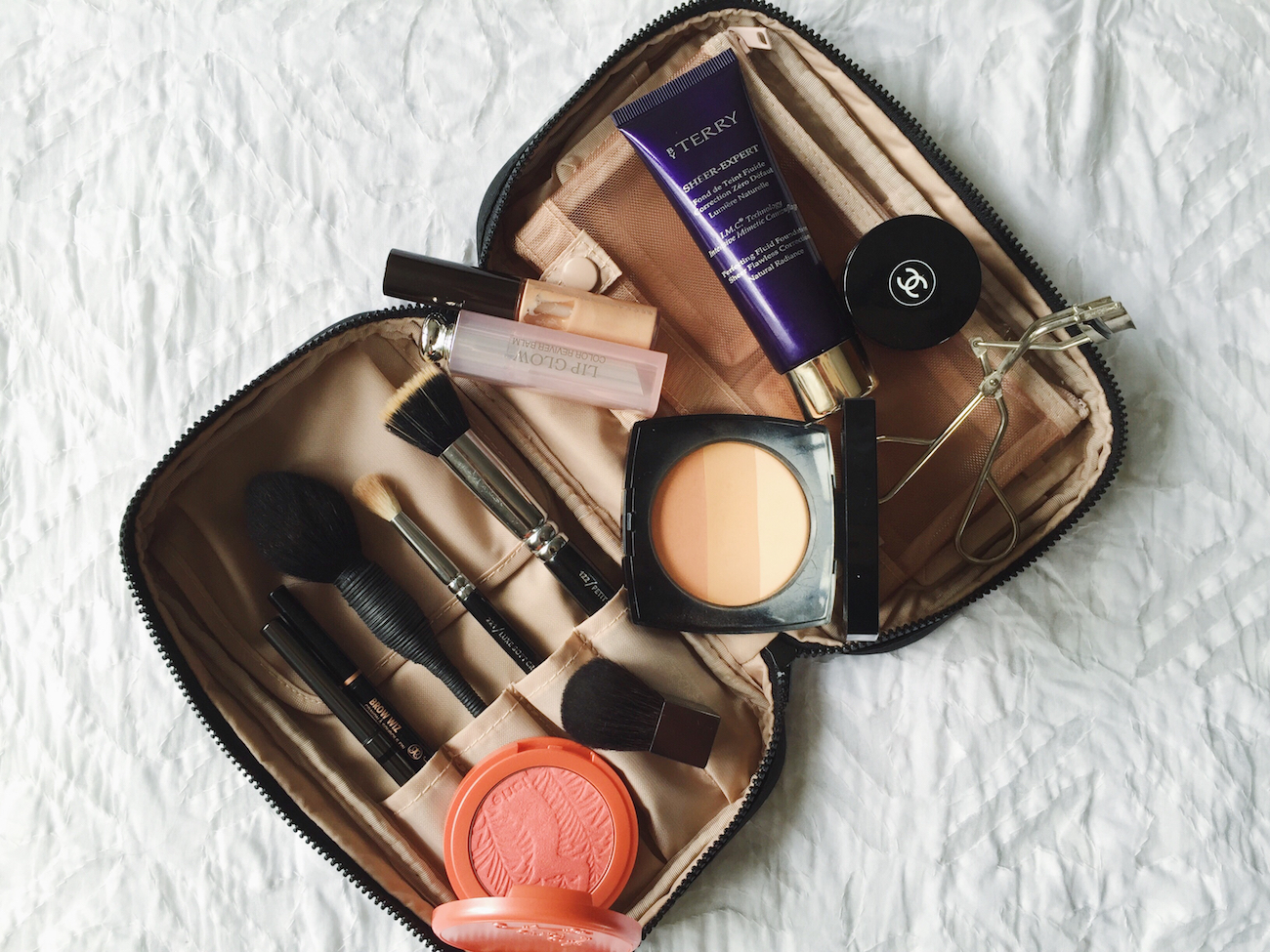An open makeup bag with French beauty brands in.