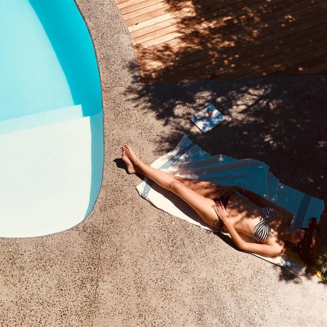 Lady sunbathing by a pool in summer. Summer skincare tips