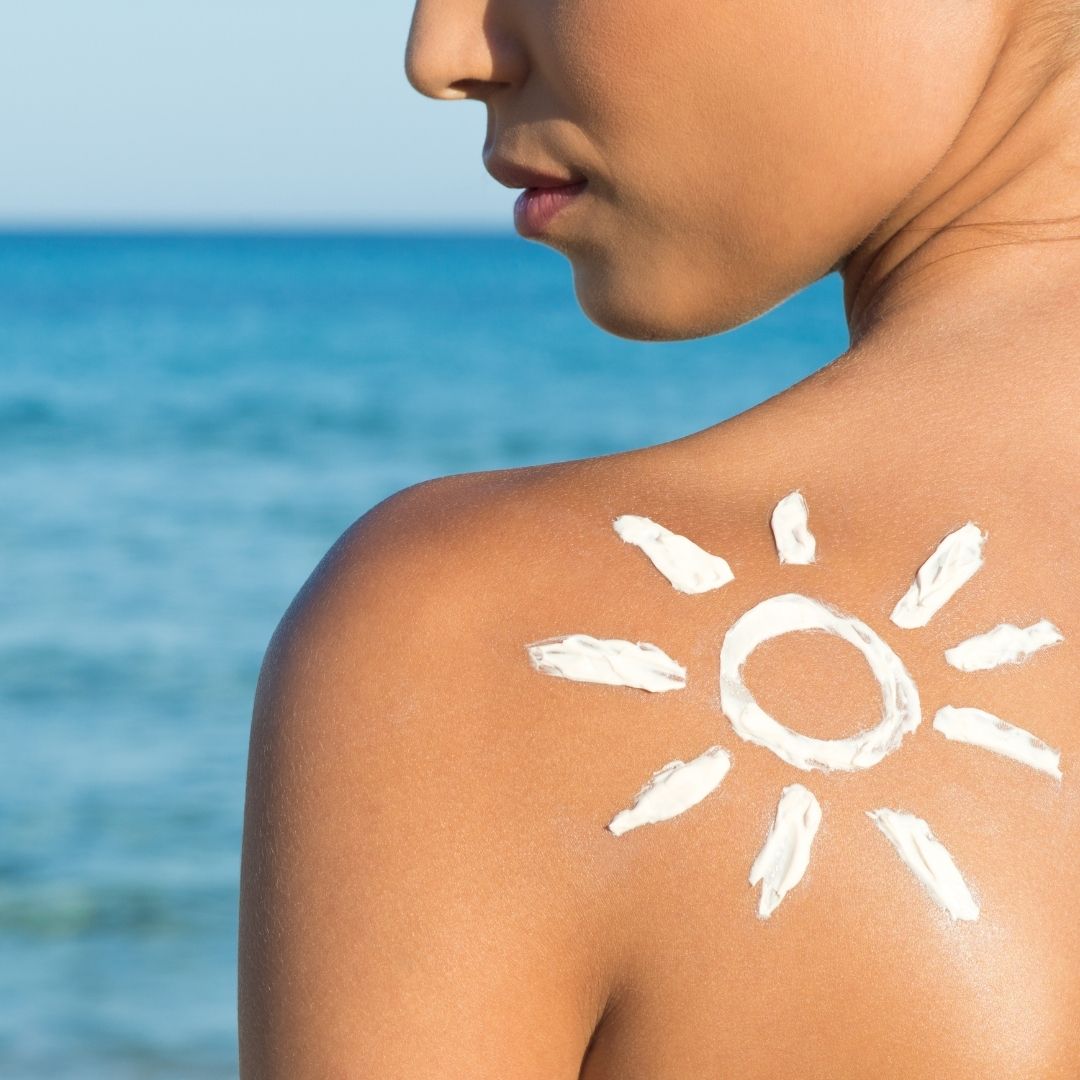 Eine in Sonnencreme eingezeichnete Sonne auf dem Rücken einer Frau, um für die Verwendung von Sonnenschutzmitteln zu werben. 
