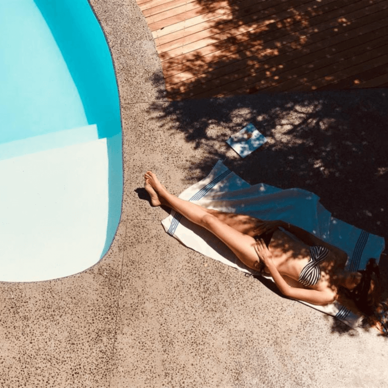 Lady sunbathing by a pool in summer. Summer skincare tips
