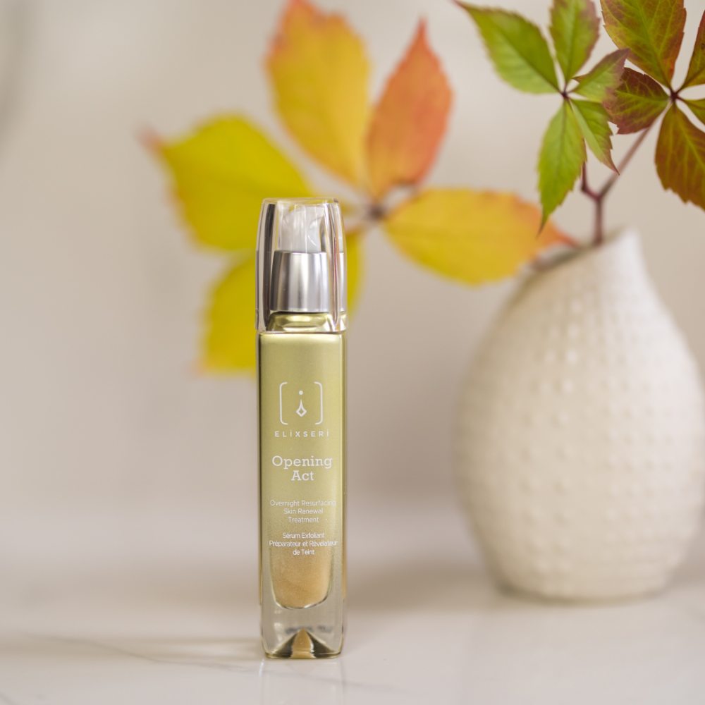 Elixseri Opening Act resurfacing serum pictured next to a white vase with Autumn leaves