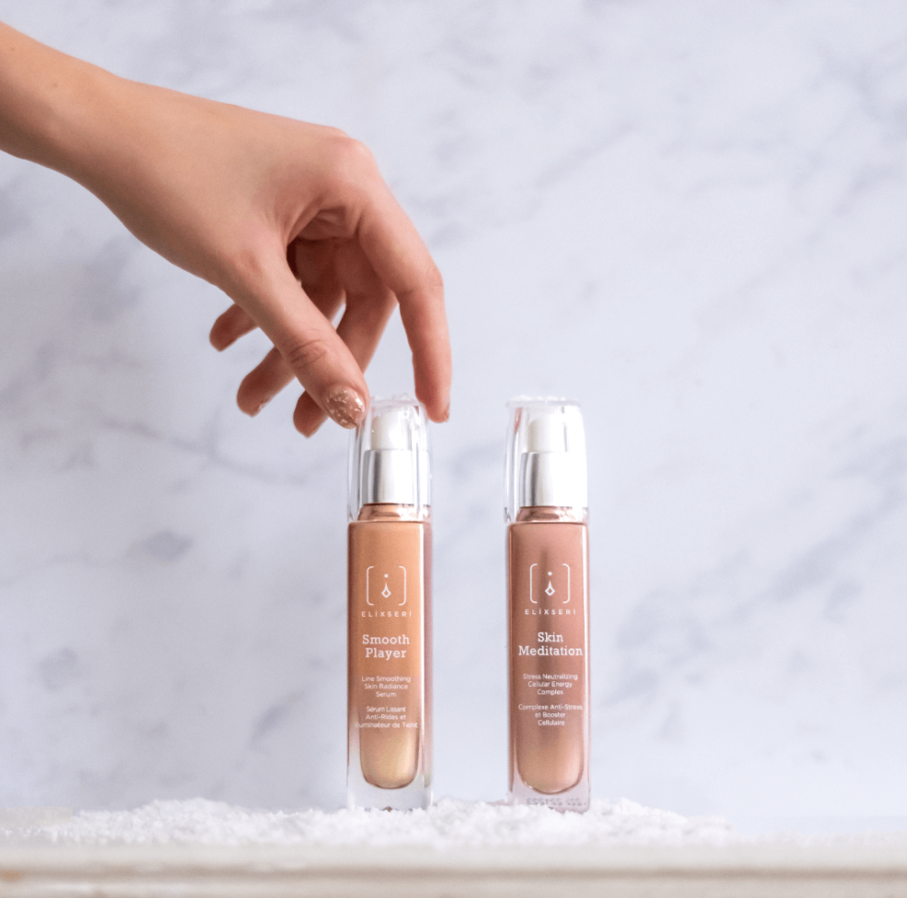 Elixseri's Winter edit - Smooth Player and Skin Meditiation. Two skin serums sat side by side in front of a marble mackground with a lady's hand picking up a serum