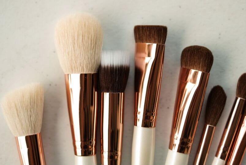 A collection of makeup brushes on a pale stone surface. Clean brushes for spring. 
