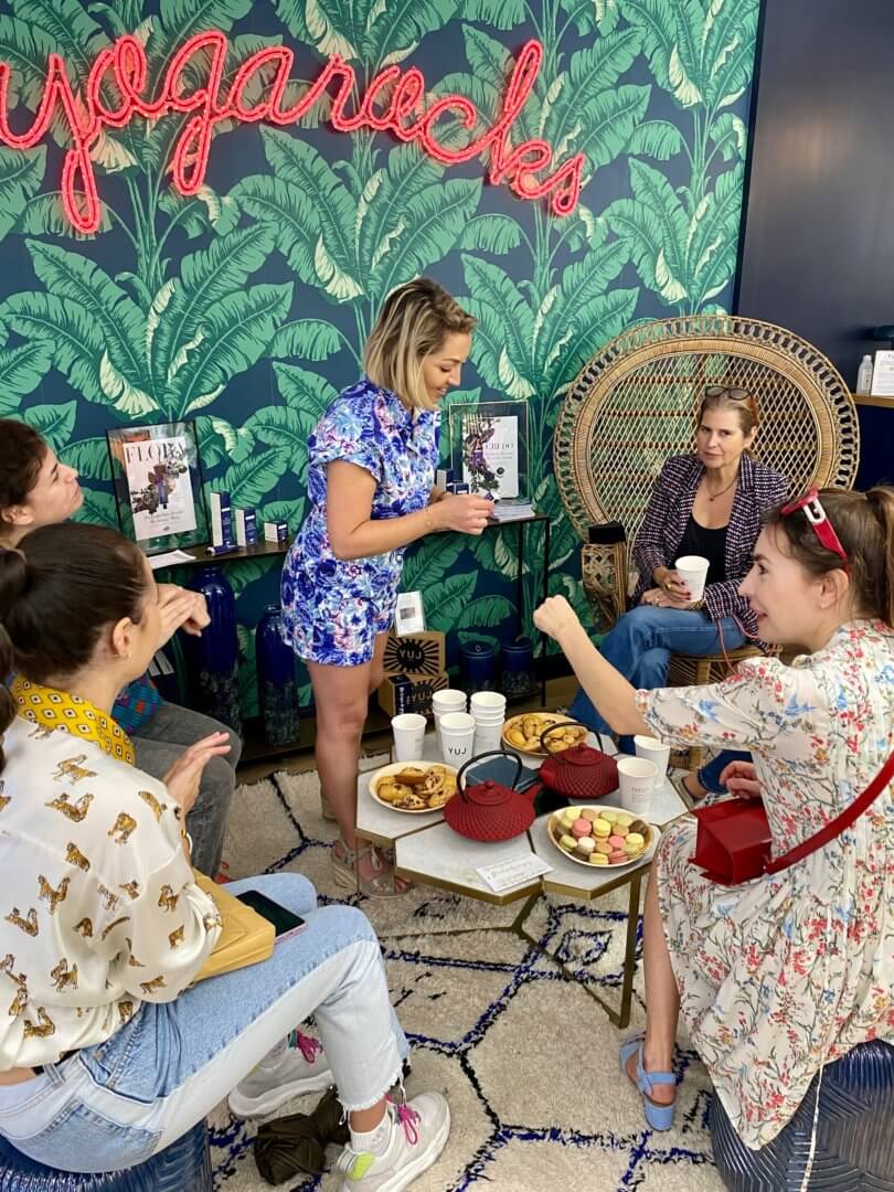 Women talking at a work meeting in a colourful room with green palm wallpaper.