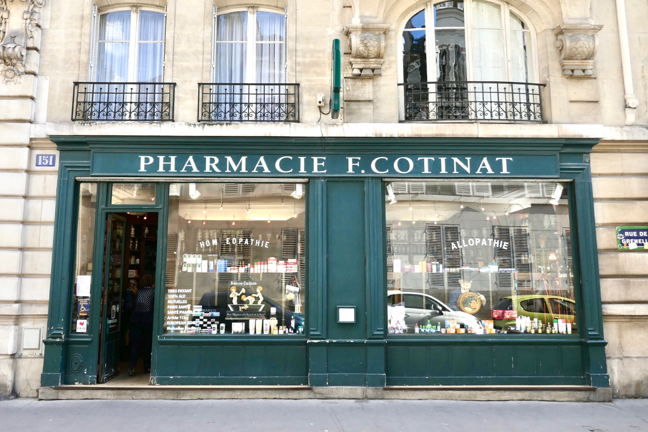 Eine französische Apotheke mit grün bemalter Fassade, die Hautpflegeprodukte verkauft.