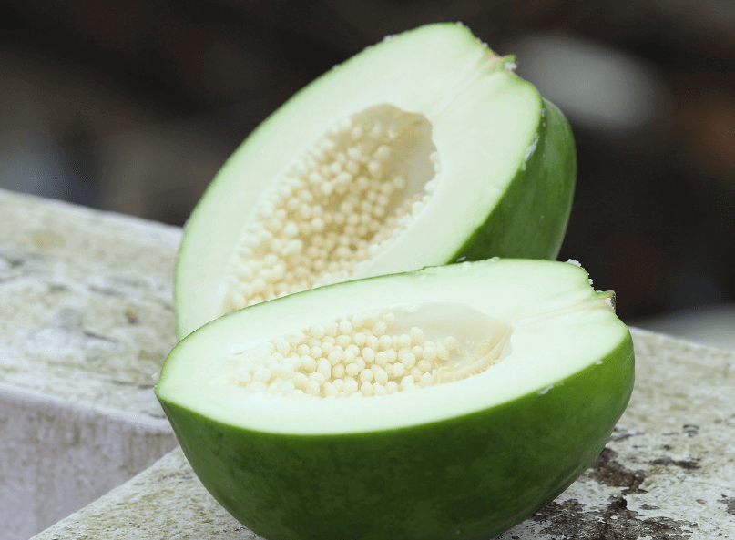 Papaye verte coupée ouverte avec ses graines visibles
