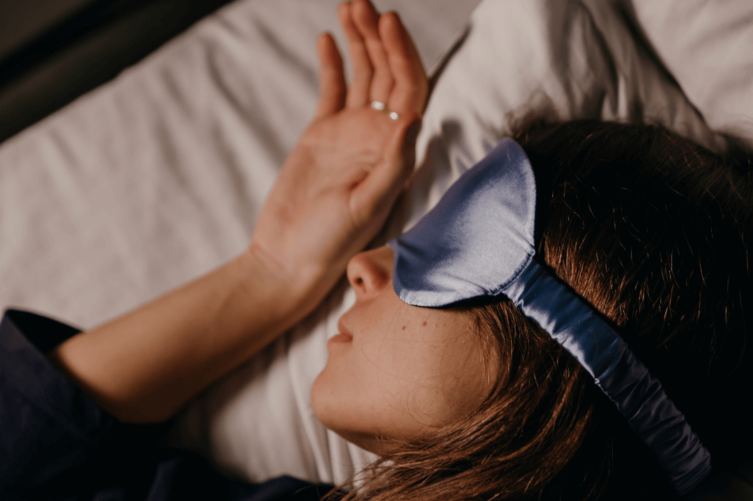 A woman sleeping wearing a silk eye mask. Getting rest in summer.