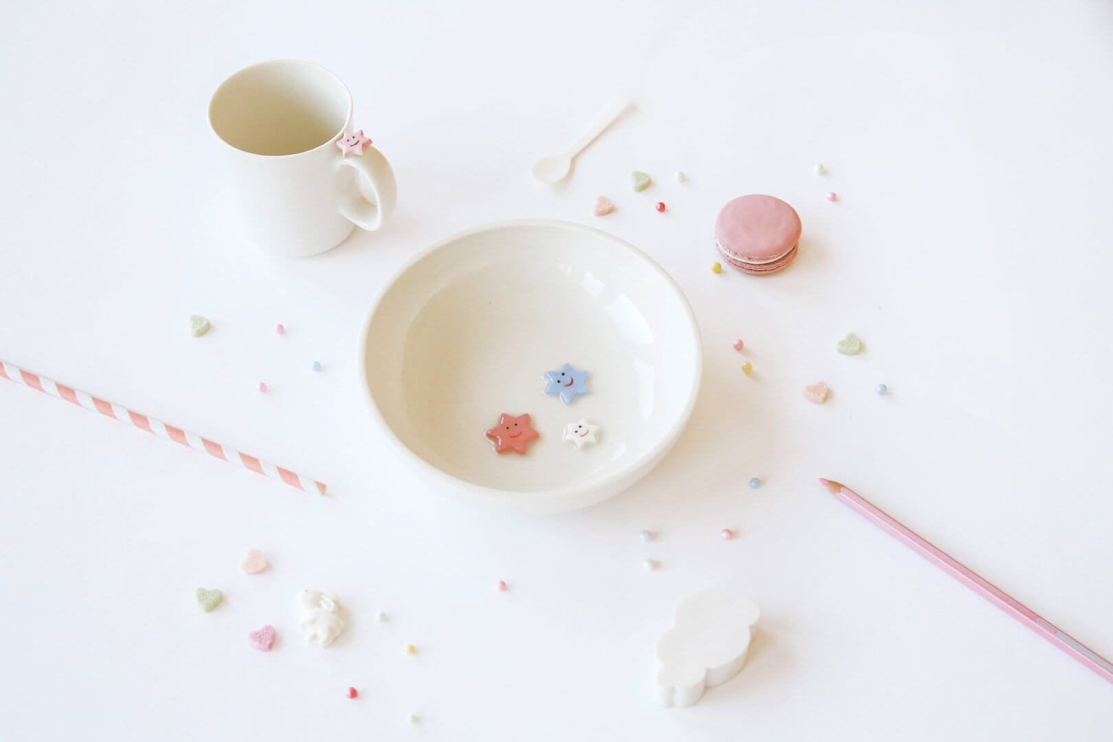 Smiling Table ceramics - un bol et une tasse faits à la main et décorés d'étoiles souriantes parmi de jolis accessoires pastel sur un fond blanc épuré.