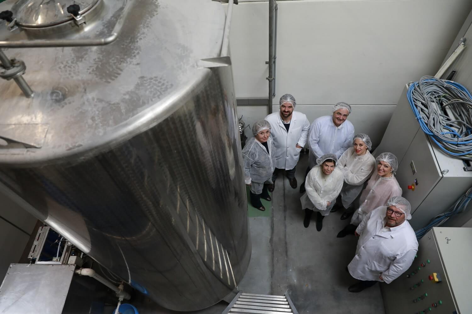 A group of Elixseri founders and scientists standing around their silver water distillation column which makes Swiss Alpine Light Water for the Elixseri serums.
